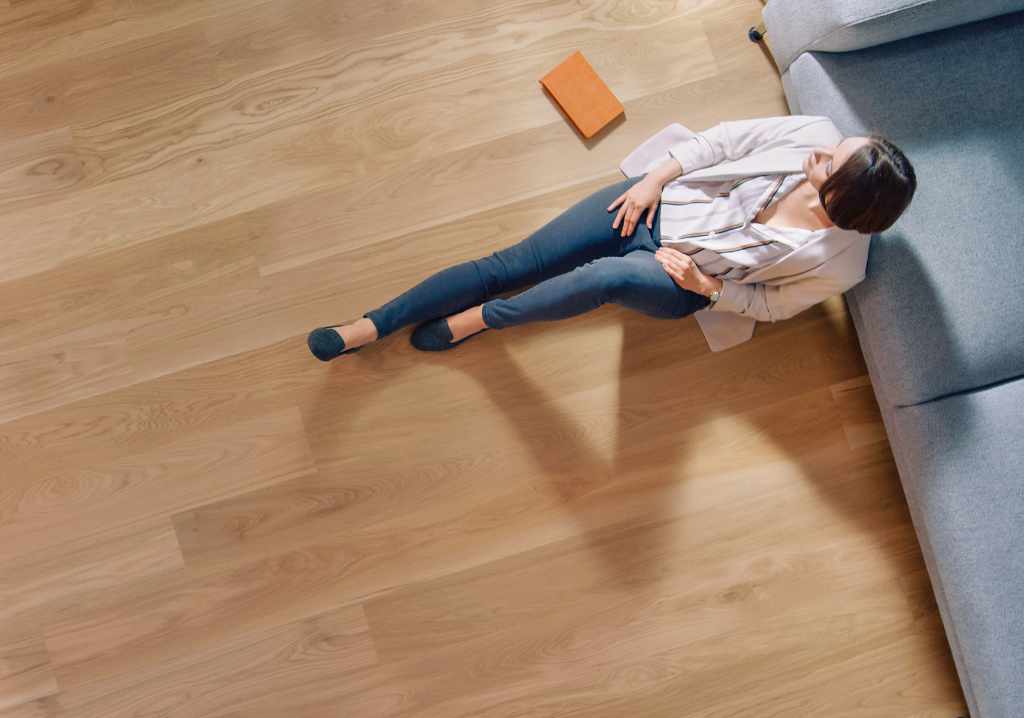 Young Woman is Sitting on a Floor and Looking out of the Window